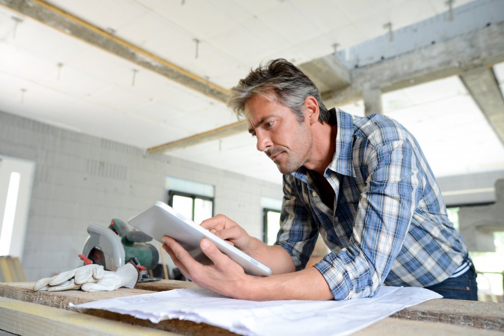 Entrepreneur in house under construction checking plan